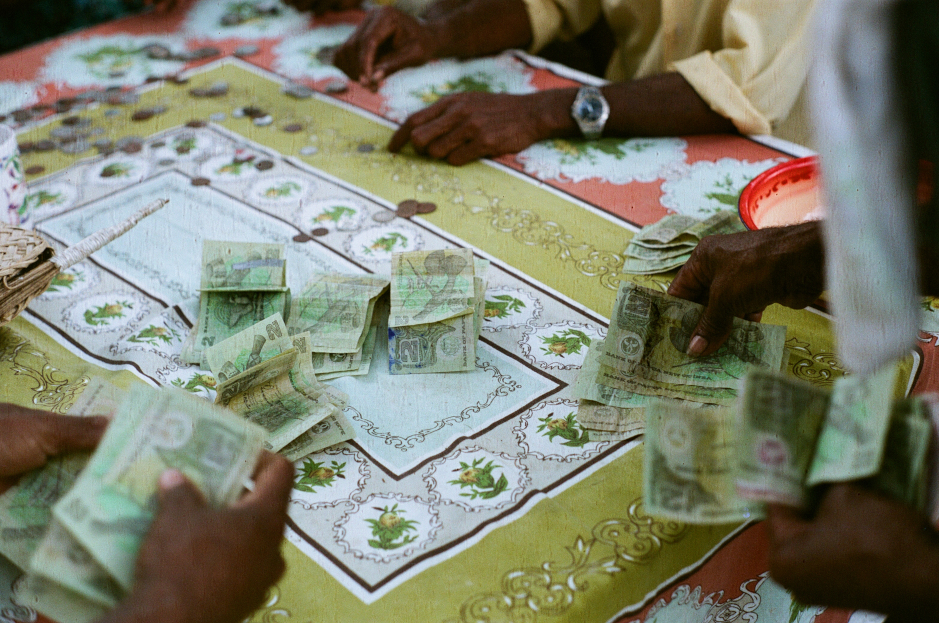 Men counting bills and coins at a table in Wadaheya, an Auhelawa village on Normanby Island, Papua New Guinea, in 2006.